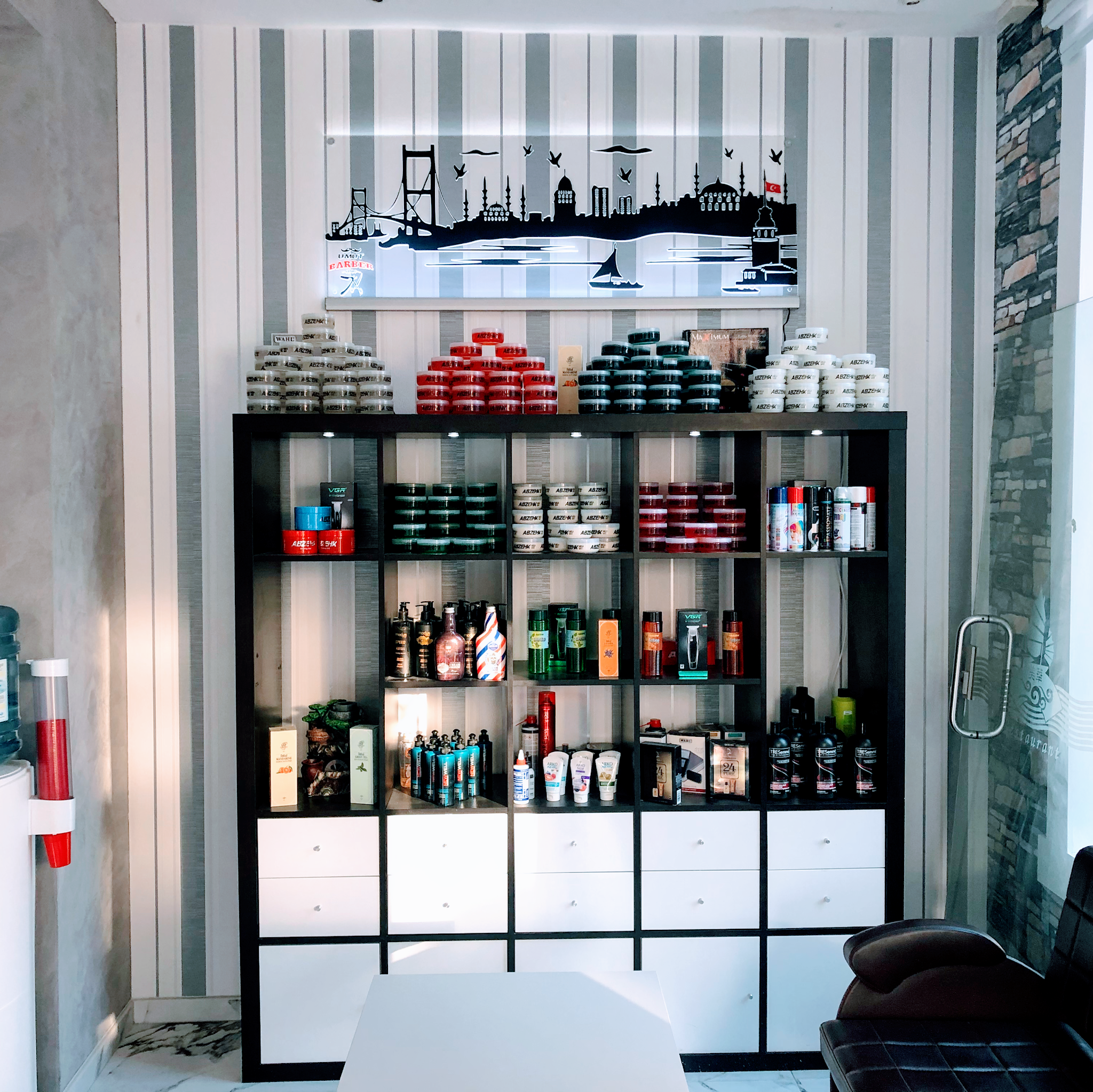 Een zwarte kast vol pomades, wax en haarproducten onder een afbeelding van de skyline van Istanbul